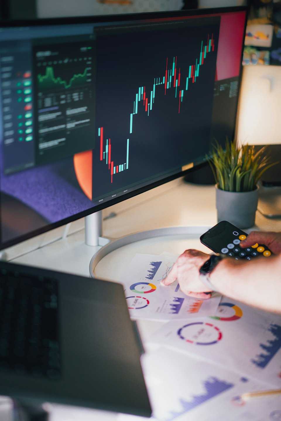 Seseorang menganalisis grafik data keuangan di atas meja putih.
